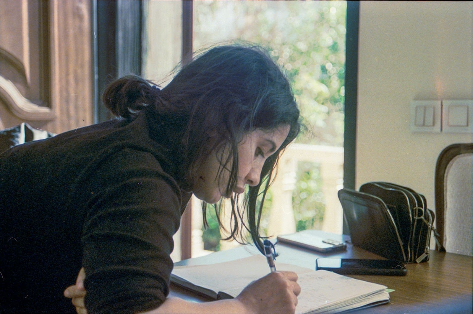 An adult learner writing in a notebook at a table, studying GCSE Maths at home